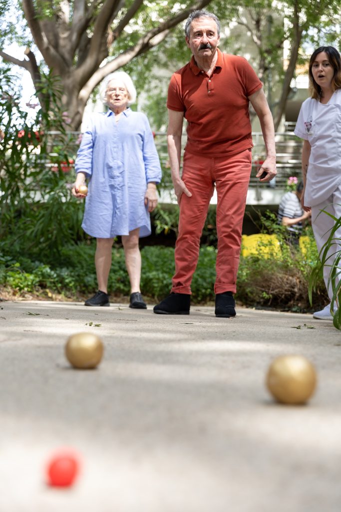 2 résidents profitant du beau temps en pleine partie de pétanque