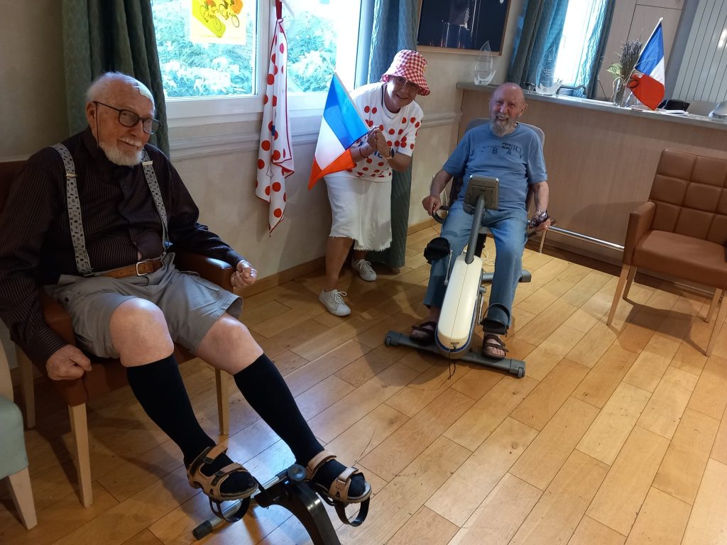 deux résidents en pleine séance de vélo, encouragés par une salarié